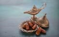 [946208216] bronze plate with dates and aladdin lamp on dark green wooden background. ramadan background. ramadan kareem